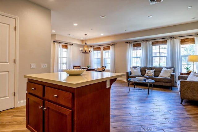 kitchen with an inviting chandelier, a center island, hanging light fixtures, and light hardwood / wood-style flooring