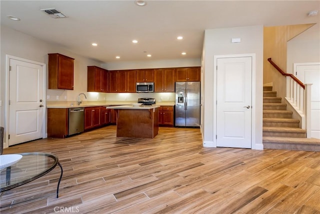 kitchen featuring stainless steel appliances, a kitchen island, sink, and light wood-type flooring