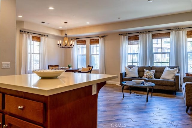 kitchen with wood-type flooring, a wealth of natural light, pendant lighting, and a notable chandelier