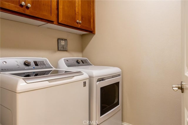 clothes washing area featuring cabinets and separate washer and dryer