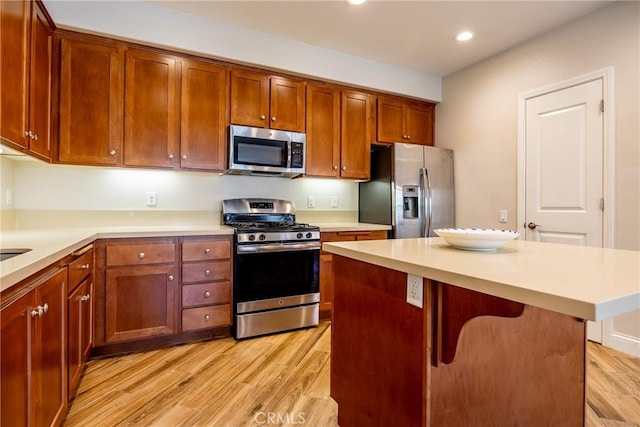 kitchen with stainless steel appliances, a center island, a breakfast bar area, and light hardwood / wood-style floors