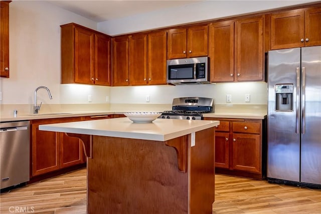 kitchen with light hardwood / wood-style flooring, a kitchen island, a breakfast bar, and appliances with stainless steel finishes