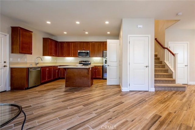 kitchen featuring stainless steel appliances, sink, a center island, and light hardwood / wood-style floors