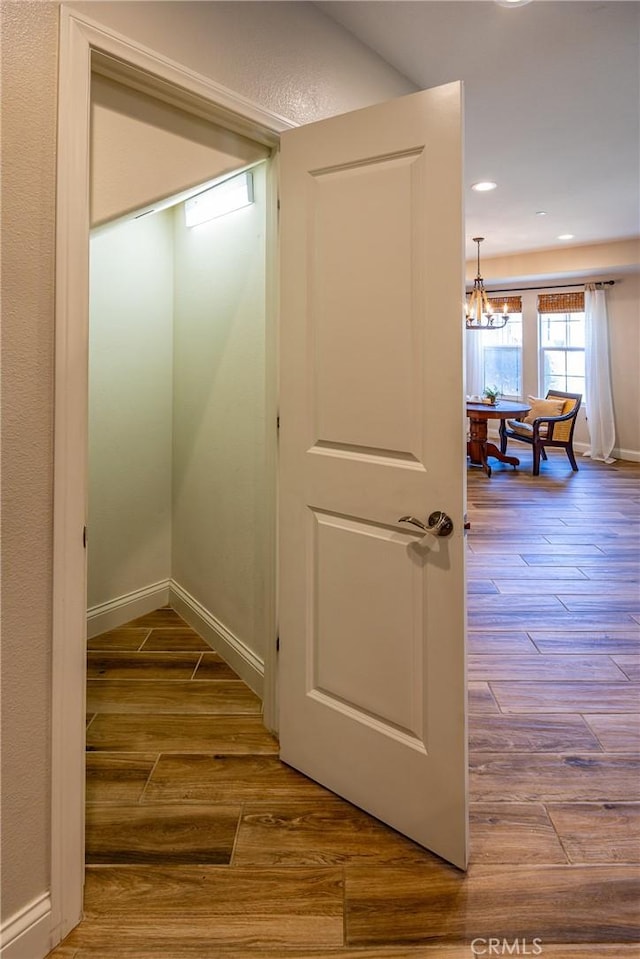 hall with hardwood / wood-style flooring and a chandelier