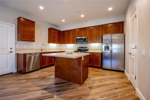 kitchen featuring sink, light hardwood / wood-style flooring, a breakfast bar, appliances with stainless steel finishes, and a center island