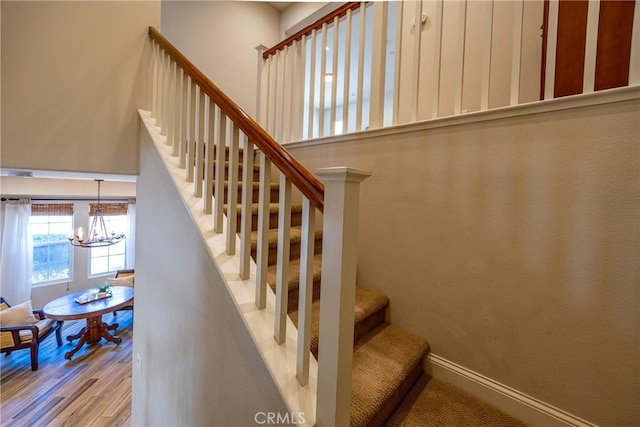 staircase featuring an inviting chandelier and hardwood / wood-style floors