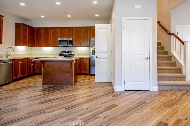 kitchen featuring stainless steel appliances, sink, a kitchen island, and light wood-type flooring