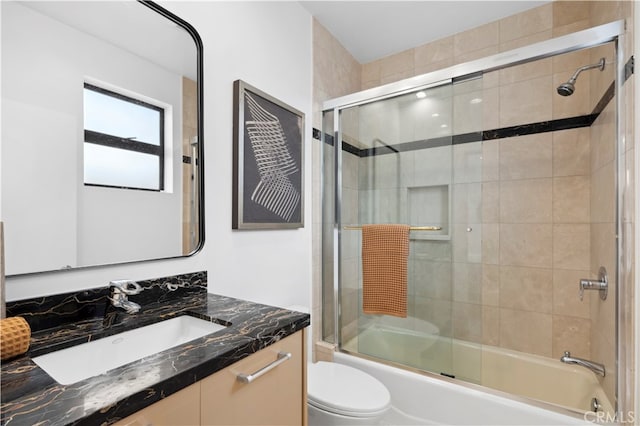 full bathroom with enclosed tub / shower combo, vanity, and toilet