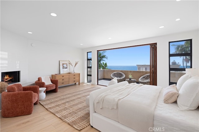 bedroom featuring light wood-type flooring and a water view