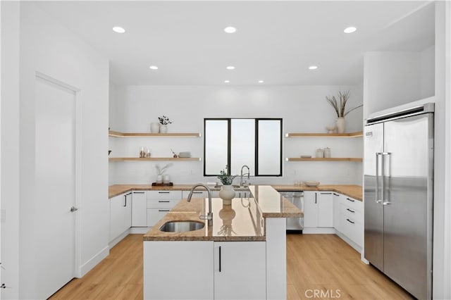 kitchen featuring light hardwood / wood-style floors, white cabinets, stainless steel appliances, a center island, and sink