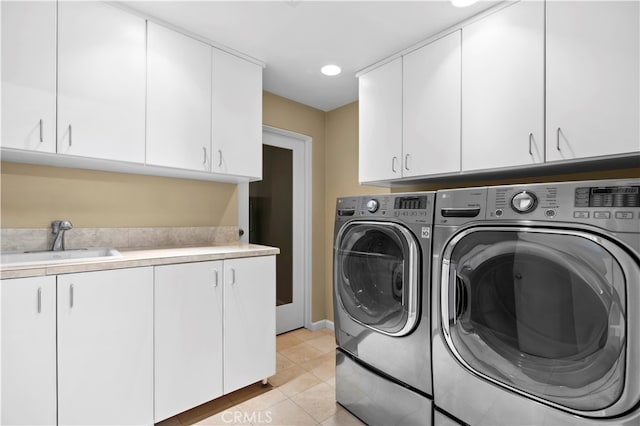 laundry area featuring cabinets, sink, light tile patterned floors, and washing machine and dryer