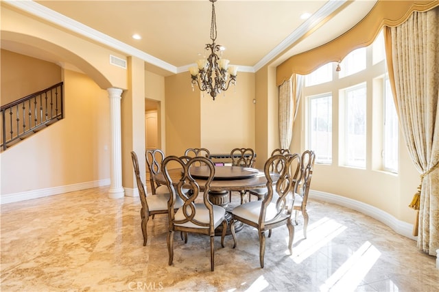 dining area featuring decorative columns, a notable chandelier, and ornamental molding