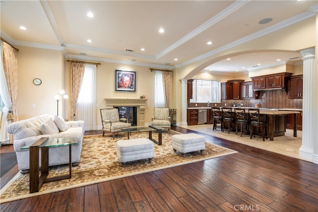 living room featuring ornate columns, light hardwood / wood-style flooring, and ornamental molding