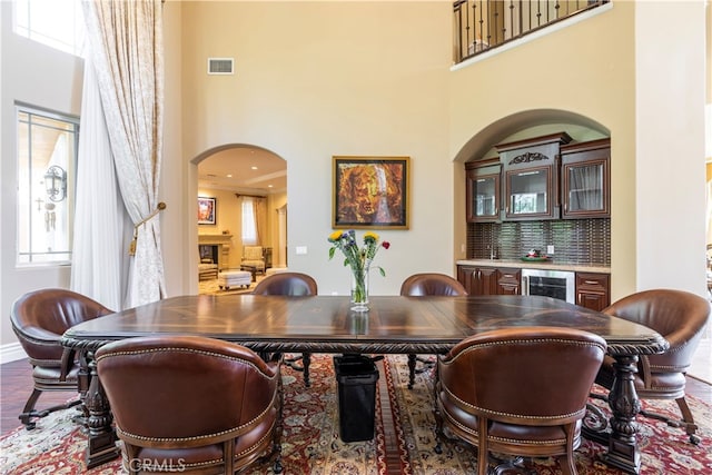 dining area featuring a high ceiling, indoor bar, and wine cooler