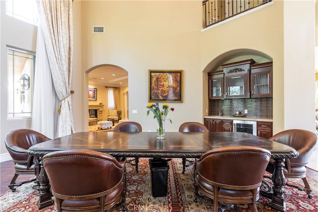 805 W Road Ln, Habra Heights, CA 90631 - dining space featuring arched walkways, a dry bar, a high ceiling, beverage cooler, and plenty of natural light