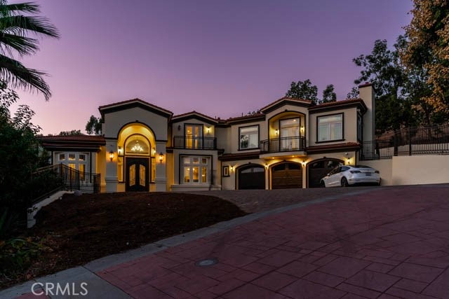 mediterranean / spanish-style home with a garage, a balcony, and french doors