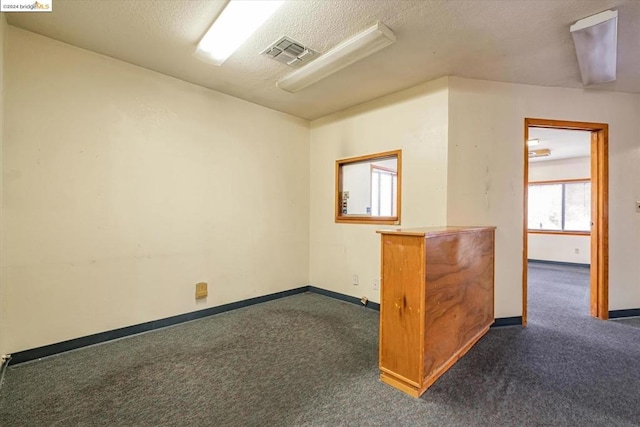 spare room with dark carpet and a textured ceiling