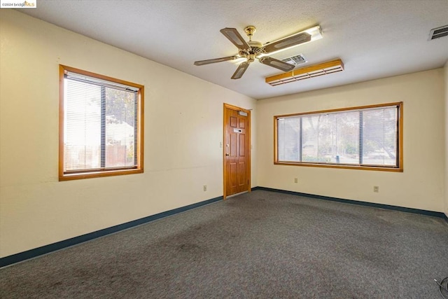 unfurnished room with dark carpet, ceiling fan, and a textured ceiling