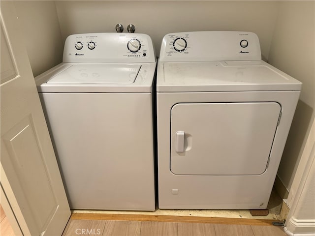 laundry room featuring separate washer and dryer and light hardwood / wood-style floors