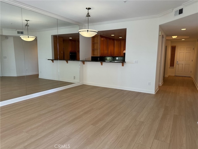 unfurnished living room with ornamental molding and light hardwood / wood-style floors