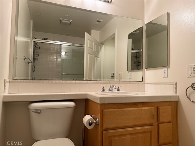 bathroom featuring backsplash, vanity, toilet, and a shower with door