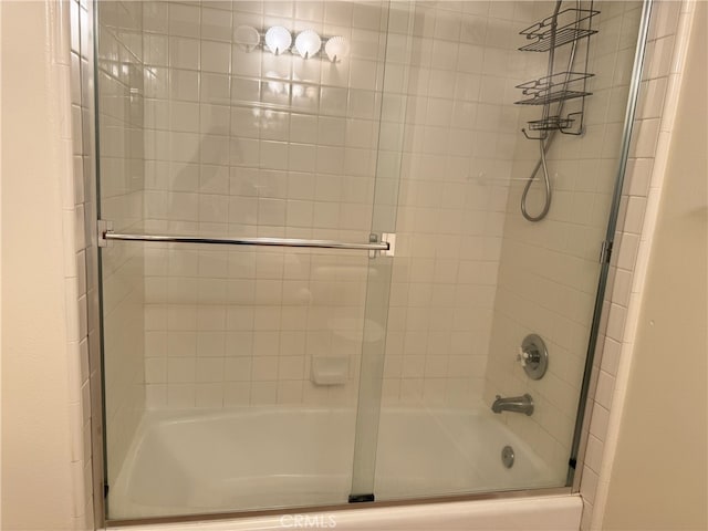 bathroom with bath / shower combo with glass door