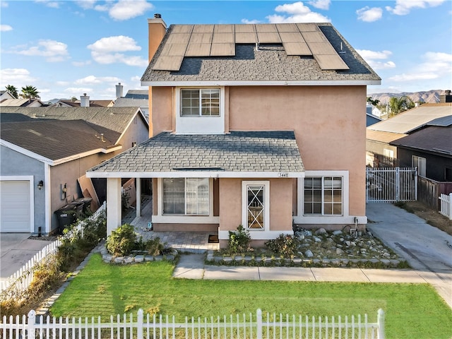 view of front of home with a garage, solar panels, and a front lawn