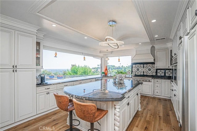 kitchen featuring a center island, backsplash, light wood-type flooring, white cabinetry, and a breakfast bar area