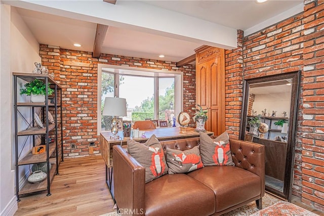 living room featuring beam ceiling, brick wall, and light wood-type flooring