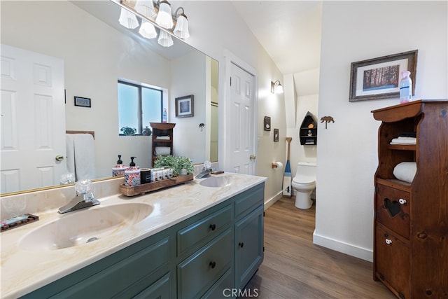 bathroom featuring wood-type flooring, lofted ceiling, vanity, and toilet