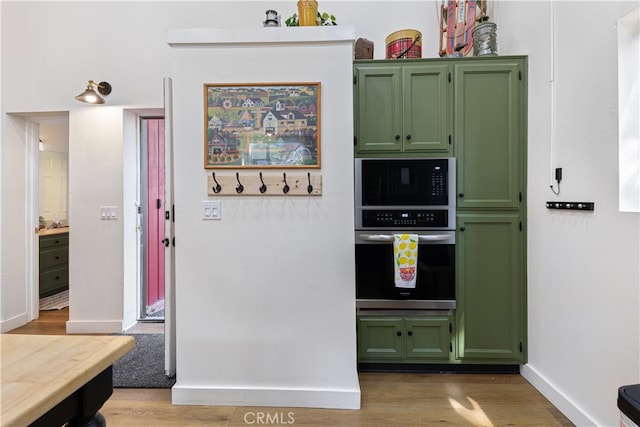 kitchen with oven, green cabinetry, and hardwood / wood-style floors