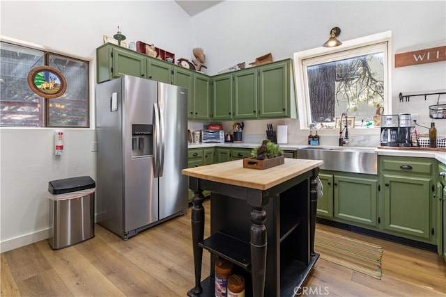 kitchen featuring lofted ceiling, sink, stainless steel refrigerator with ice dispenser, green cabinets, and light wood-type flooring