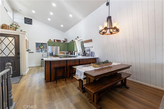 30897 Glen Oak Dr, Running Springs, CA 92382 - kitchen with green cabinetry, stainless steel fridge, wood finished floors, a chandelier, and a peninsula