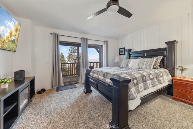 carpeted bedroom featuring access to outside, wooden walls, and ceiling fan