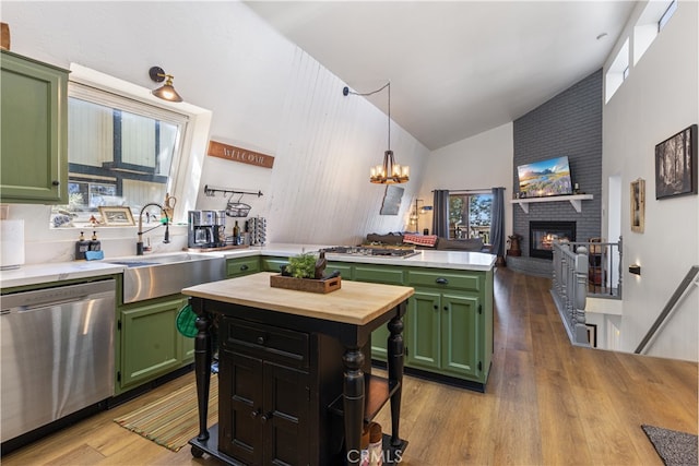 kitchen with a brick fireplace, green cabinetry, stainless steel appliances, and a kitchen island