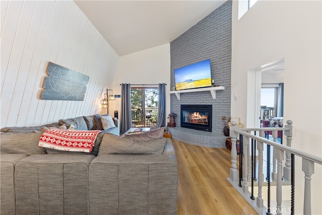 living room with a healthy amount of sunlight, a fireplace, high vaulted ceiling, and hardwood / wood-style flooring