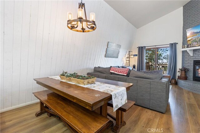 30897 Glen Oak Dr, Running Springs, CA 92382 - living room featuring high vaulted ceiling, wood finished floors, a chandelier, wood walls, and a brick fireplace