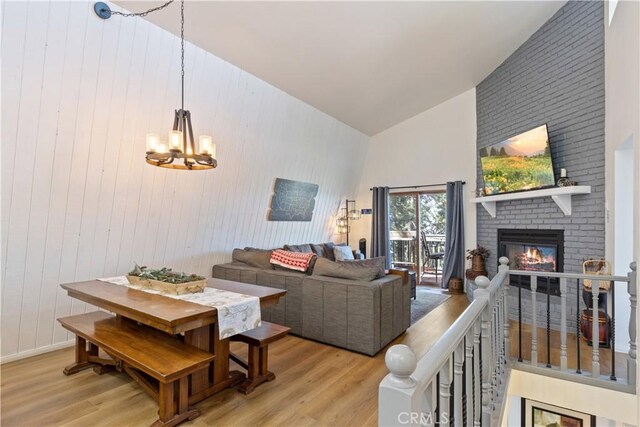 30897 Glen Oak Dr, Running Springs, CA 92382 - living room with light wood-type flooring, high vaulted ceiling, a chandelier, a fireplace, and wooden walls