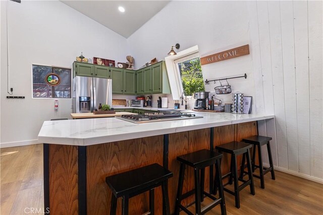 30897 Glen Oak Dr, Running Springs, CA 92382 - kitchen with green cabinetry, stainless steel appliances, a peninsula, light wood-style floors, and high vaulted ceiling