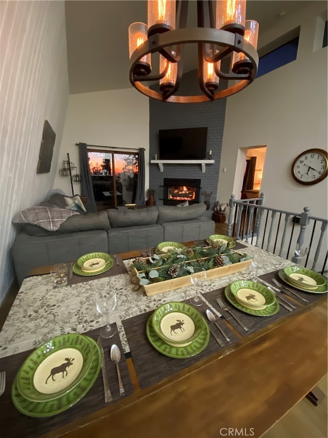 living room with a brick fireplace, an inviting chandelier, and a high ceiling