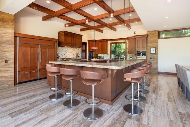 kitchen with backsplash, a kitchen breakfast bar, coffered ceiling, beamed ceiling, and decorative light fixtures