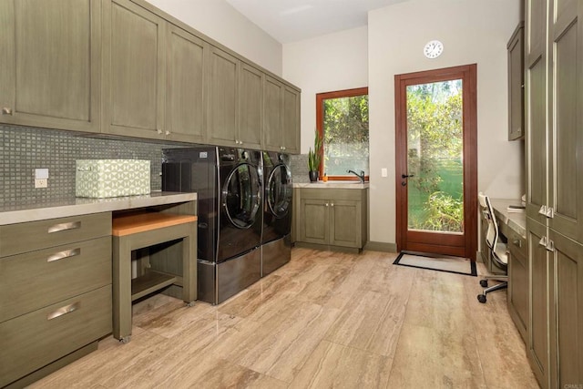 laundry area featuring sink, light hardwood / wood-style flooring, washer and clothes dryer, and cabinets