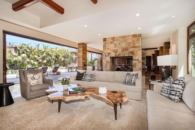 living room with a large fireplace, hardwood / wood-style flooring, beamed ceiling, and a wealth of natural light