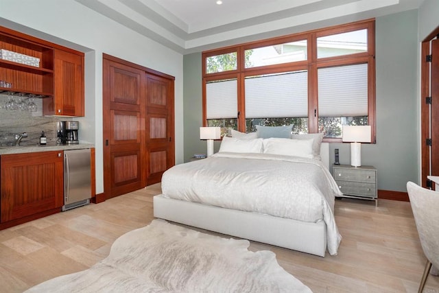 bedroom with stainless steel refrigerator and light hardwood / wood-style flooring