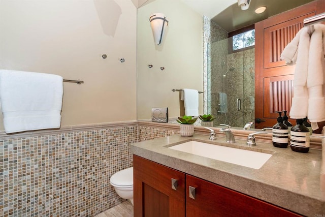 bathroom featuring tile walls, vanity, a shower with shower door, and toilet