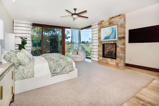 bedroom with ceiling fan, expansive windows, light hardwood / wood-style flooring, and a multi sided fireplace