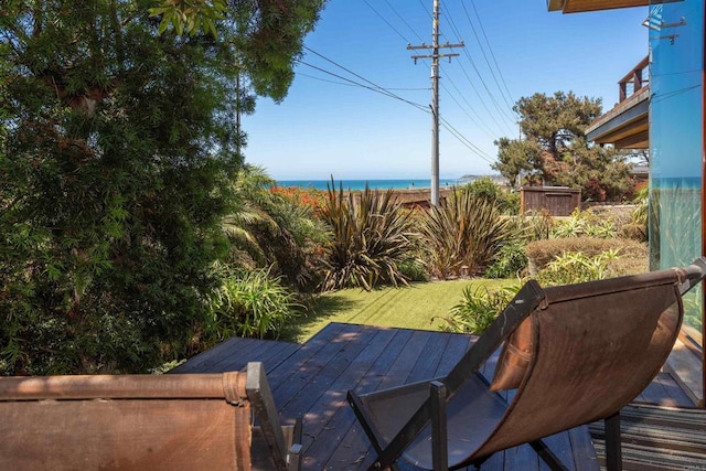 wooden deck featuring a shed, a water view, and a lawn