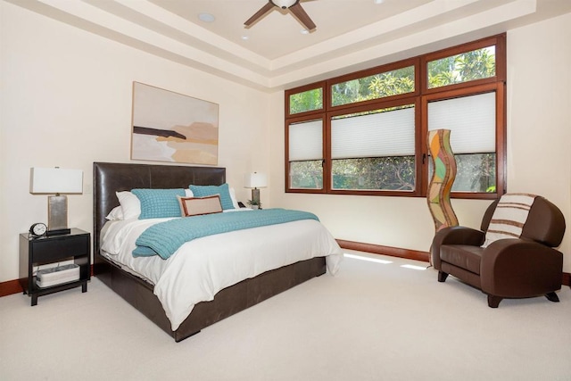 carpeted bedroom featuring a tray ceiling and ceiling fan