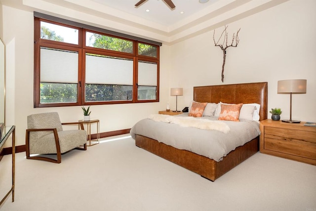 carpeted bedroom with a raised ceiling and ceiling fan