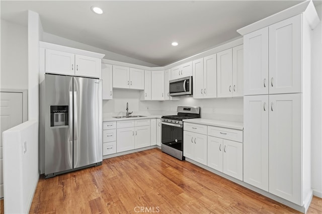 kitchen featuring light hardwood / wood-style floors, stainless steel appliances, sink, and white cabinetry